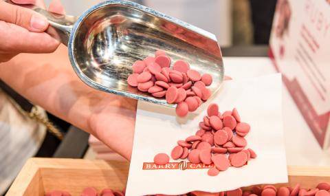 Ruby chocolate wafers being scooped into a napkin by a booth attendee