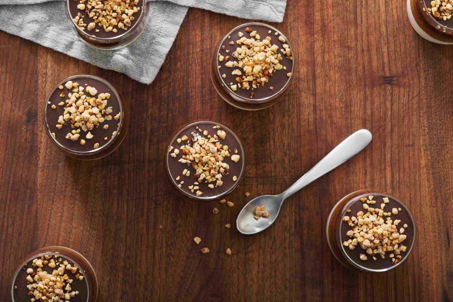 small cheesecakes in glass containers with a spoon on a table