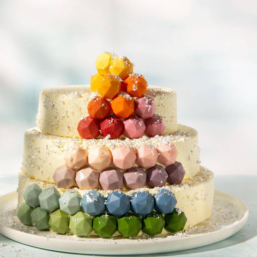 Tiered cake decorated with multicolored pralines and silver flakes