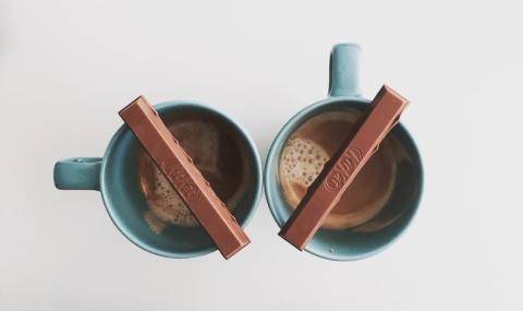 cups of coffee with a kit kat bar laying across the rim of the cup