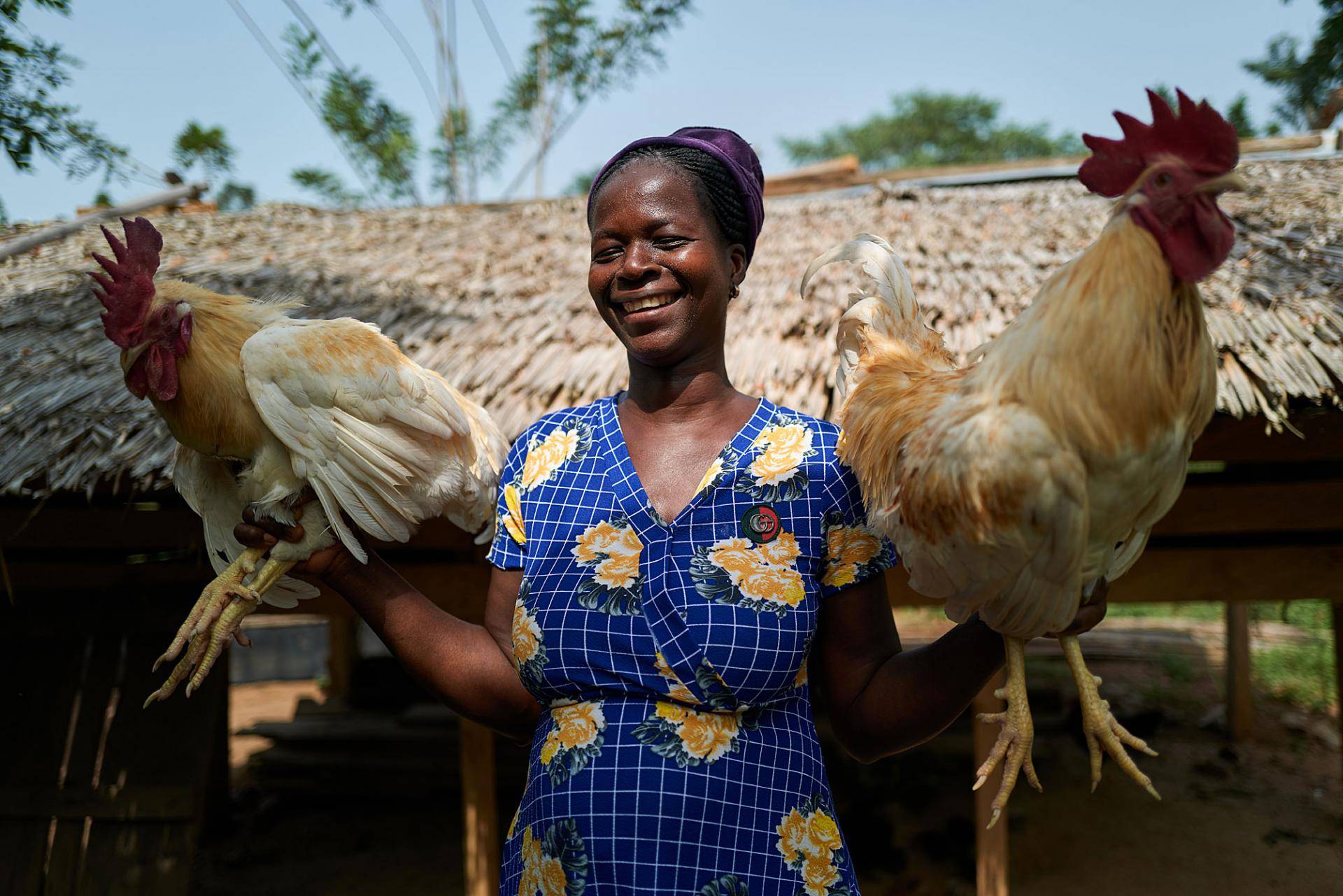 Empower the women Esther holding two roosters from her own farm
