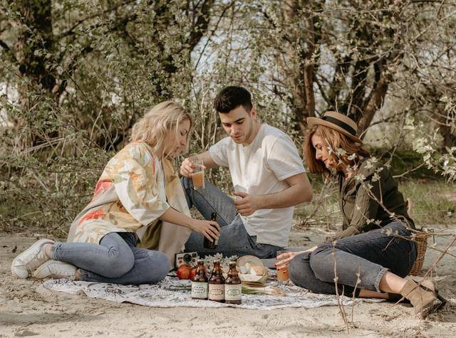 three friends sitting on a picnic blanket 