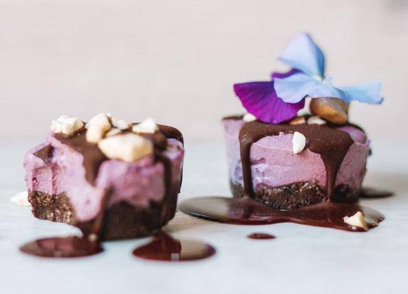 two vegan cakes that are purple with flowers on top
