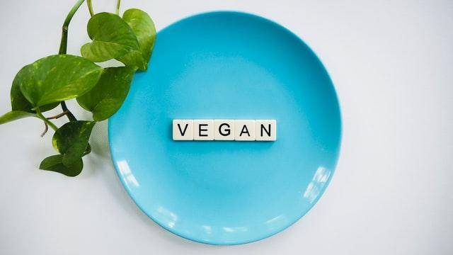 a blue plate with scrabble letters on it spelling out "vegan"