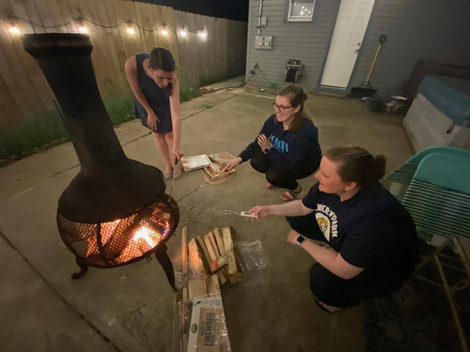 Friends gather round a fire in their backyard. Photo by kelseymoher.com