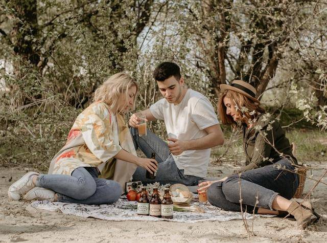 three friends sitting on a picnic blanket