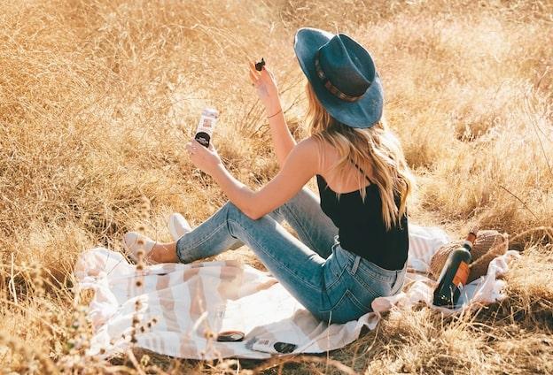 woman sitting on blanket in field eating snack