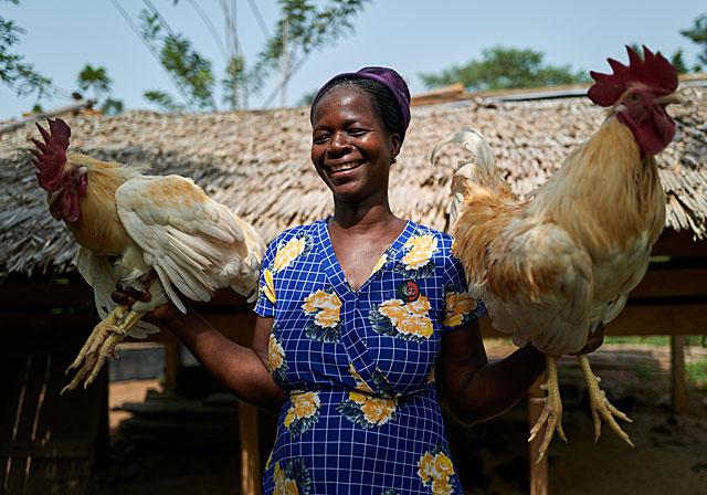 Empower the women Esther holding two roosters from her own farm 