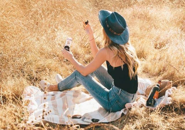 woman sitting on blanket in field eating snack